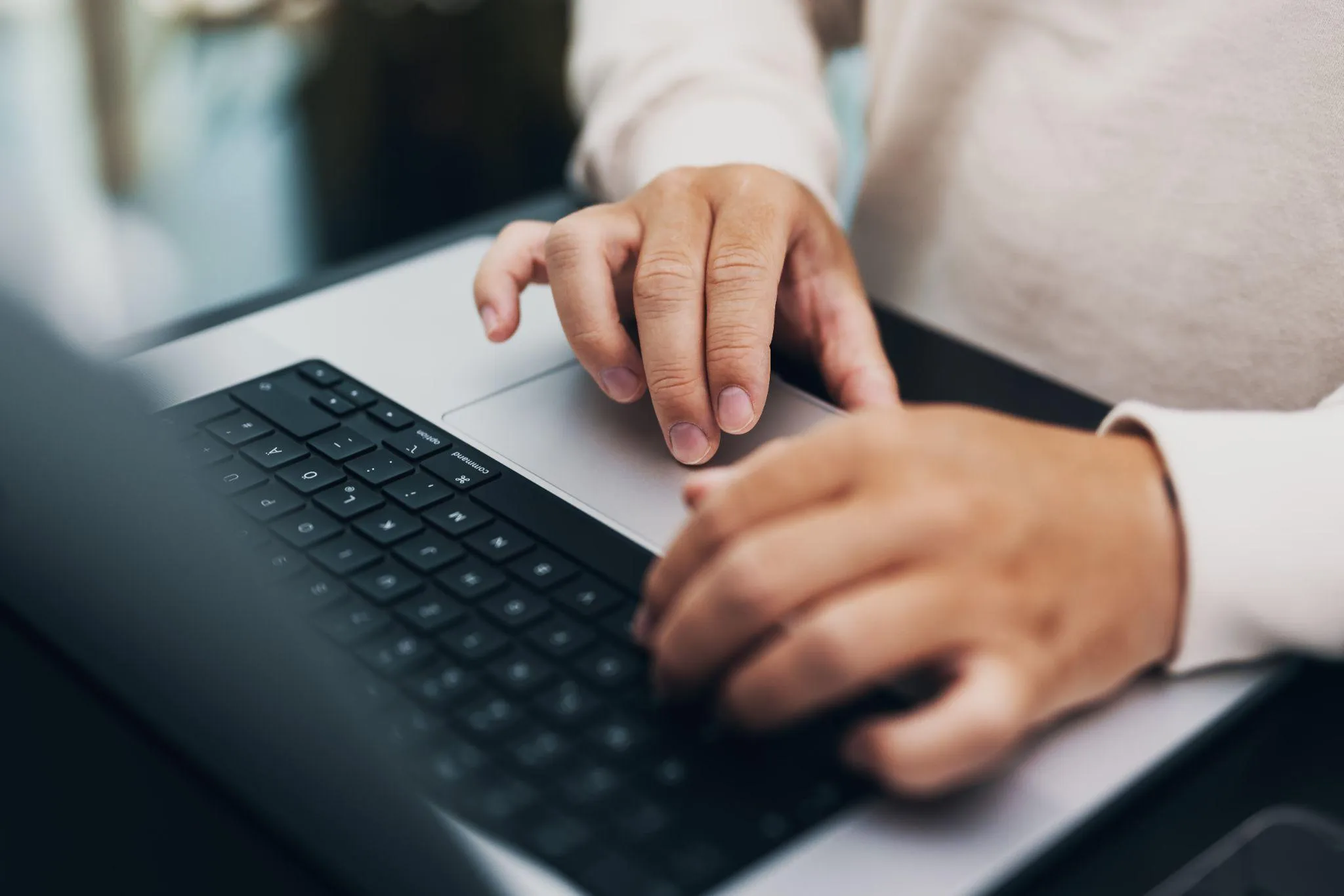 Hände auf Tastatur und Trackpad eines MacBooks